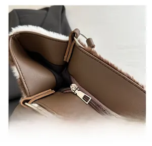 Close-up of silver zipper closure on brown faux leather and white plush bucket bag