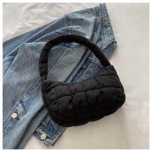 Detailed view of black quilted puff shoulder bag with soft padded handle and grid texture