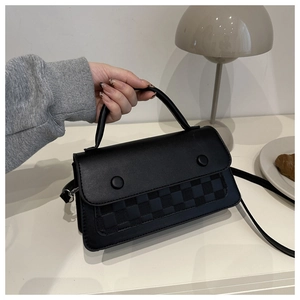 Detail view of black PU leather shoulder bag with checkerboard pattern and dual round buckles
