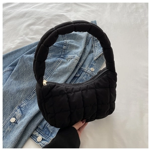 Detail of black quilted cloud bag with puffy grid stitching and golden zipper closure