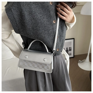Detail shot of a silver metallic crossbody bag featuring a checkered woven texture