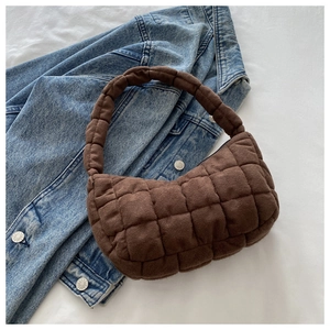 Detail of dark brown quilted puffer tote bag with suede texture on denim background
