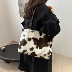 Detailed shoulder view of a soft cow-print plush tote bag with brown leather strap detail