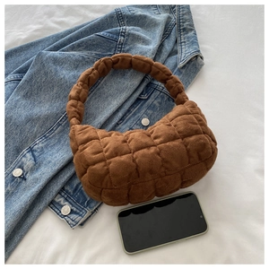 Detailed view of brown quilted suede handbag with phone for size reference