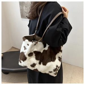 Detail of plush cow print shoulder bag with brown faux fur and leather strap