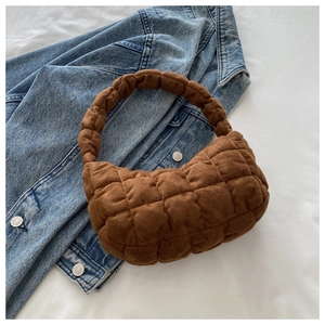 Close-up of caramel brown quilted faux suede handbag on denim jacket with textured finish