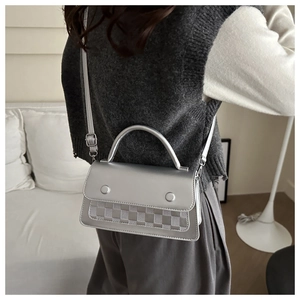 Silver textured crossbody bag with checkerboard embossing shown in a home setting