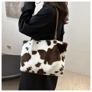 Detailed side view of large cow print faux fur tote bag showing fluffy texture and strap