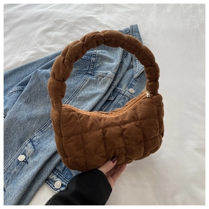 Detail of caramel brown quilted velvet bag with braided handle and metallic zipper