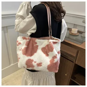 Détail d'un sac cabas en peluche imprimé vache avec bandoulière rose porté par un mannequin