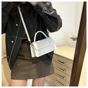 Detail of white crossbody bag featuring elegant checkered embossing and top handle