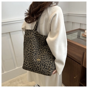 Gros plan du sac fourre-tout léopard avec plaque logo en métal et sangle en nylon