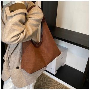 Bruine suède hobo tas met brede schouderriem gedragen door een model in casual stijl