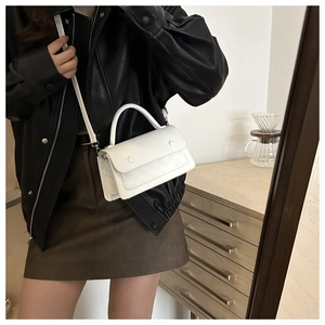 Close-up of white crossbody bag with checkered texture and circular decorative buckles