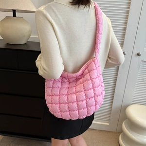 Quilted bright pink nylon shoulder bag styled on model in a modern interior setting