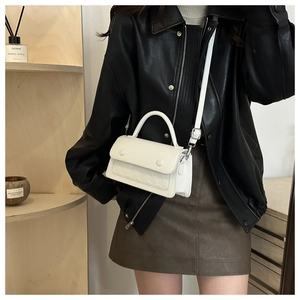 Detailed close-up of white crocodile pattern flap bag with adjustable leather shoulder strap