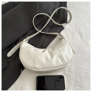 Detailed view of cream crescent crossbody bag with stitch accents and adjustable strap