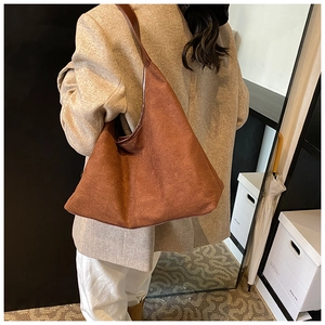 Detail of large dark brown matte suede tote bag worn as an underarm shoulder bag