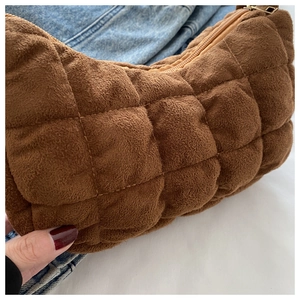 Close-up of brown quilted plush fabric and detailed stitching on half-moon shoulder bag