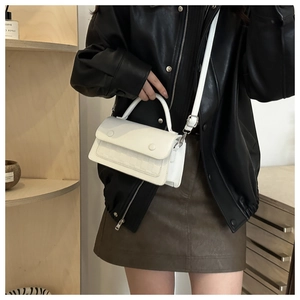 Detail of white PU leather crossbody bag featuring woven embossed flap texture on display