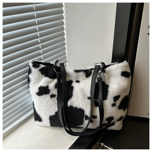 Close-up of cow print faux fur tote bag showing plush texture and black leather strap