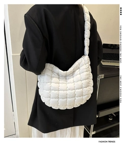 Detail of white quilted puffer bag with checkerboard pattern on black blazer