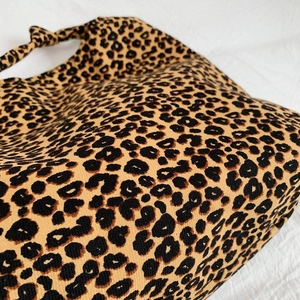 Chic leopard print large shoulder bag with knotted strap on white textured background
