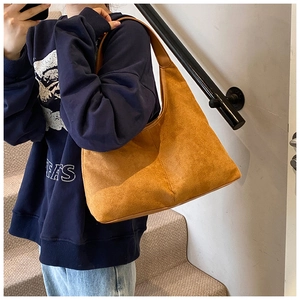 Close-up of brown suede hobo bag worn on shoulder by model in a stylish casual setting