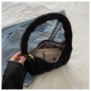 Internal view of black quilted puffer handbag showing storage space for phone and wallet