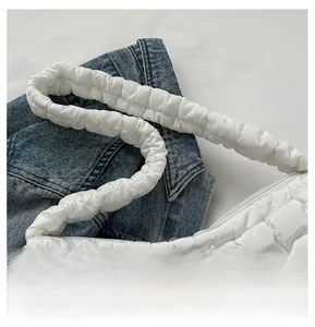 Detail of white quilted crossbody bag showing wide padded shoulder strap and soft texture