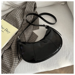 Top view of glossy black crescent shoulder bag with silver hardware on fabric