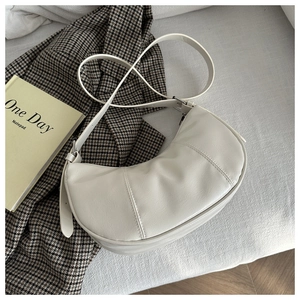 Detail showing cream white crescent bag texture with vertical seams and adjustable strap