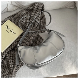Close-up of a silver crescent hobo bag with sleek vertical stitching and adjustable strap