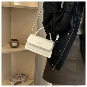 Detail of a white minimalist PU leather crossbody bag with silver buckle and top handle