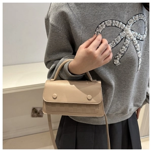 Detail of light beige plaid embossed mini bag worn with casual outfit on crossbody style