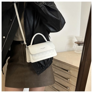 Detail view of white leather crossbody bag with FASHION TREND embossed text and slim strap