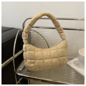 Close-up of beige quilted shoulder bag with grid texture on industrial metal shelf