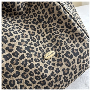 Vue détaillée du tissu léopard en toile avec un badge en métal doré fait à la main