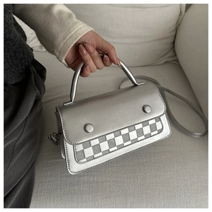 Detail of silver matte crossbody bag with checkerboard pattern and dual button closure