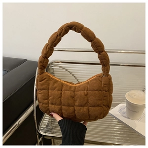 Detailed close-up of brown quilted shoulder bag with bubble texture and square stitching