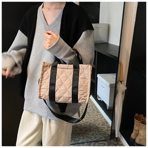 Detail of a quilted nylon crossbody bag with contrast handles and adjustable shoulder strap