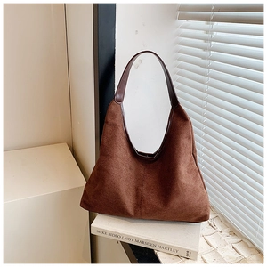 Detail van donkerbruine matte suède hobo tas op een boek in natuurlijk raamlicht