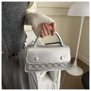 Detail of silver crossbody bag featuring checkered pattern base and metallic finish