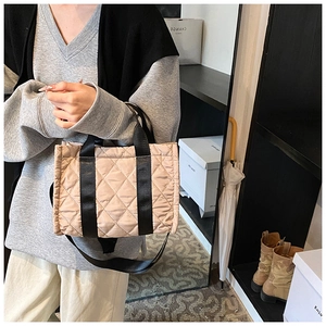 Detailed view of pink quilted rhombus tote bag with black canvas handles and strap