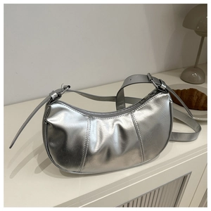 Detailed close-up of silver crescent bag with pleated texture and adjustable strap