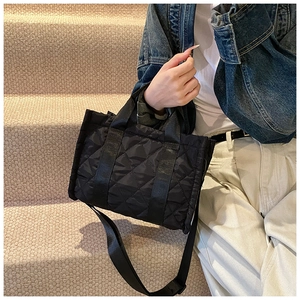 Foto lifestyle di una borsa tote trapuntata nera portata a tracolla su una scala