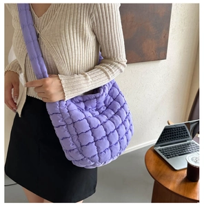 Detail view of purple quilted crossbody bag with soft padding and wide strap on model
