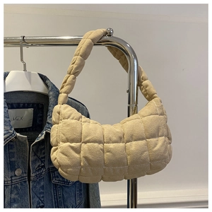 Close-up of beige quilted shoulder bag with textured fabric and cloud-style design