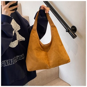 Close-up of caramel suede tote bag with middle seam detail worn by a model in a casual setting