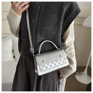 Close-up of a silver leather crossbody bag with a classic checkerboard pattern detail